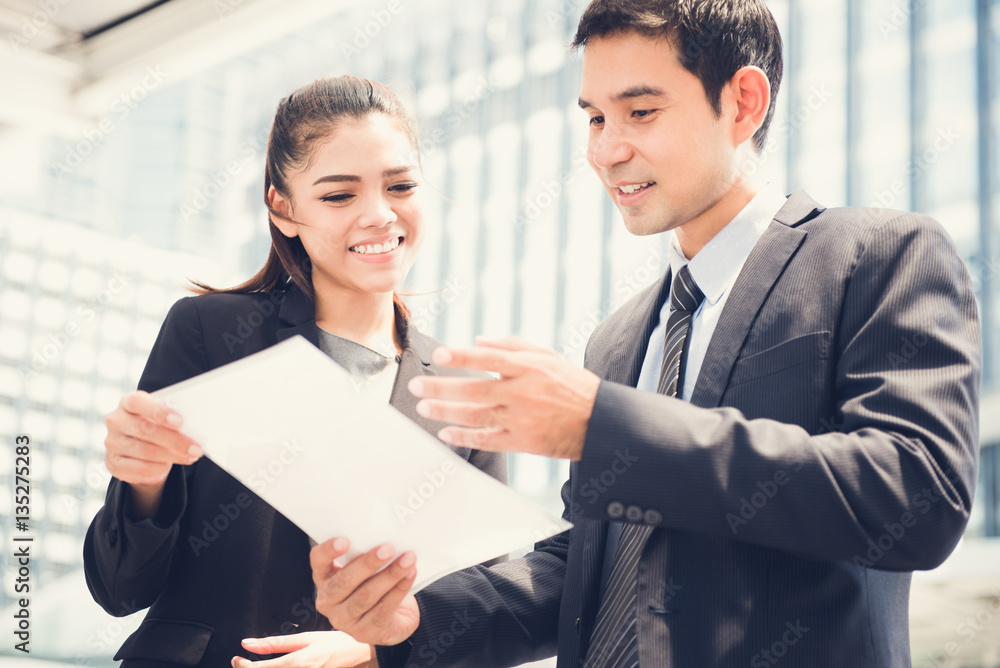 Asian businesswoman and businessman discussing document Asian businesswoman and businessman discussing document