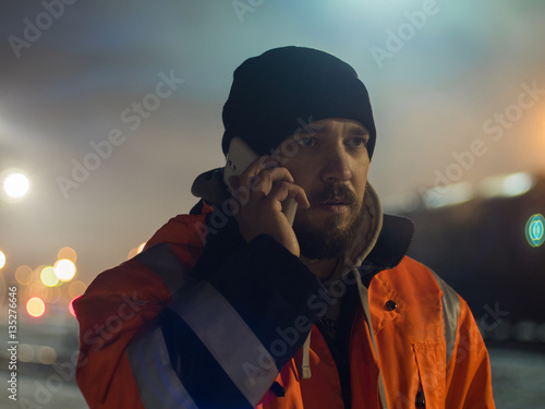 Worker talking by smartphone bokeh light in bacground. Concept of night shift