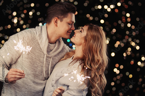 Cheerful couple in winter clothes hugging and kissing. Low light