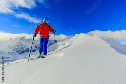 Fototapeta Mountaineer backcountry ski walking up along a snowy ridge with