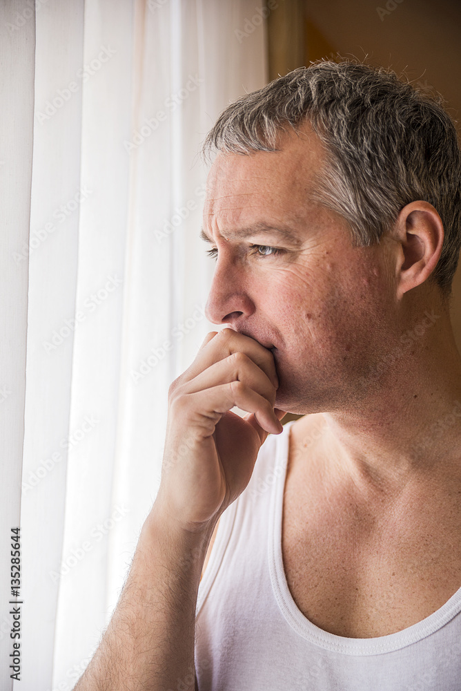 Fototapeta premium Sad man looking out the window. Feeling hopeless. Depressed mature man