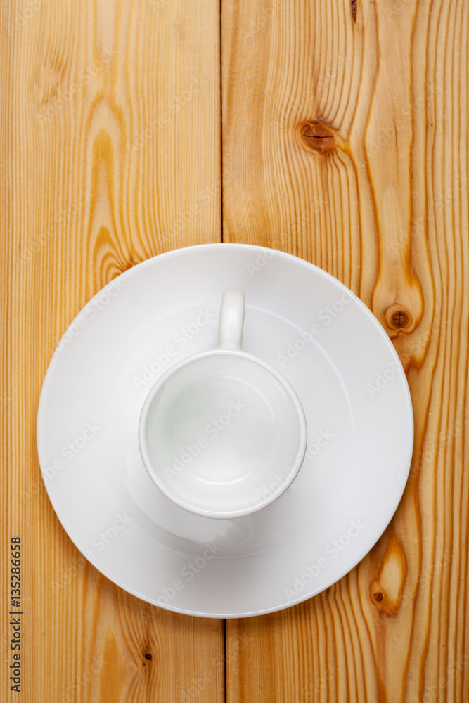 Empty ceramic cup with plate on a wooden table, top view, vertical Empty ceramic cup with plate on a wooden table, top view, vertical