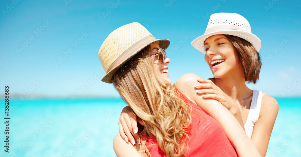 happy young women in hats on summer beach