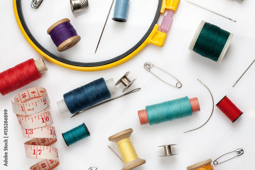Spools of thread, needles and other sewing stuff on a white background, flat lay composition, close-up