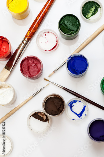 Flat lay composition with gouache jars and paintbrushes isolated on white, top view, vertical