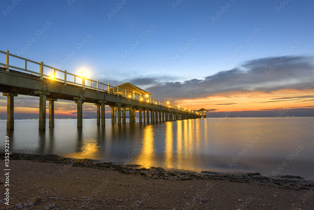 wooden bridge laying into the sea at sunset scenery