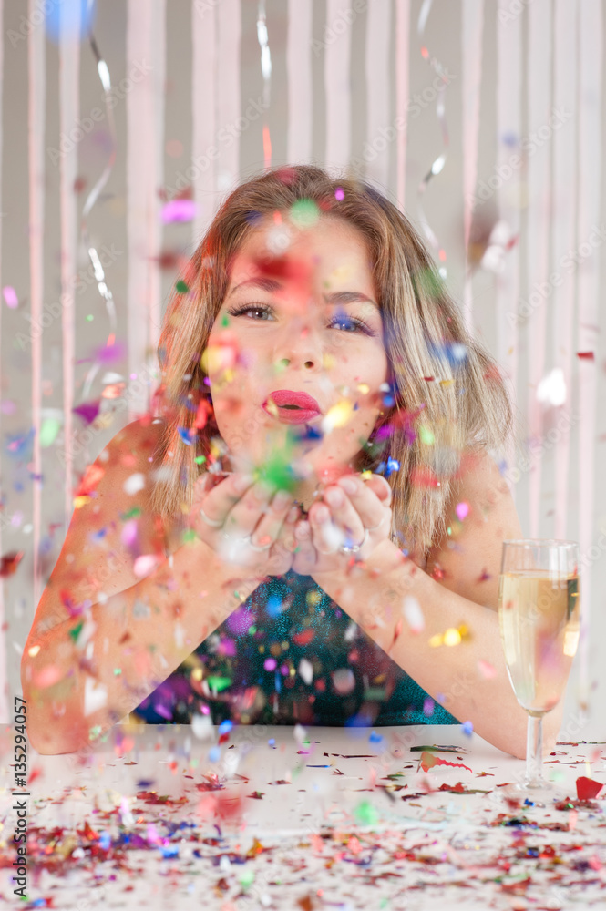Happy girl blowing colourful glitter at a party