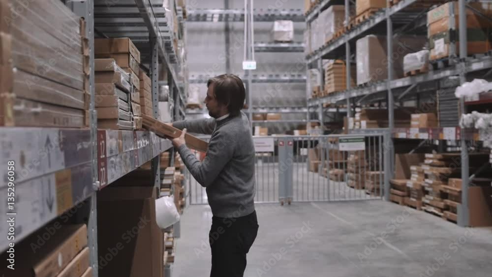 worker moving, taking out, putting, segregating, lifting on from shelves in warehouse. Man with box in modern stock worker moving, taking out, putting, segregating, lifting on from shelves in warehouse. Man with box in modern stock