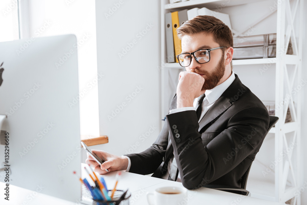 Concentrated young bearded businessman using computer Concentrated young bearded businessman using computer