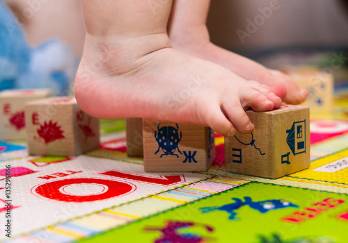 Children's leg standing on the Developing rug with children's cubes