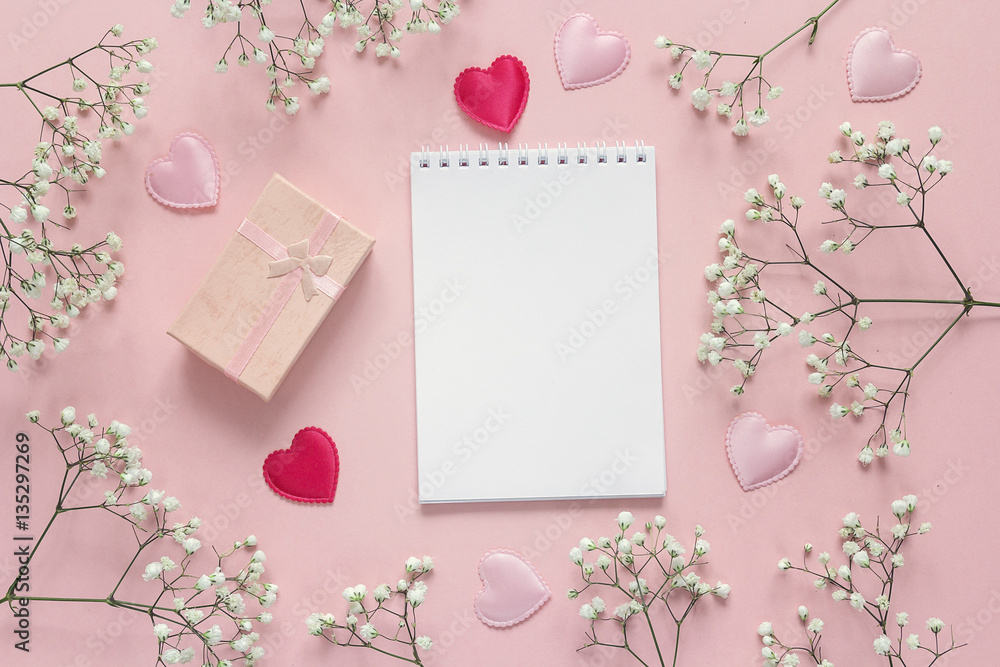 Open blank notebook with gift box, small white flower and hearts