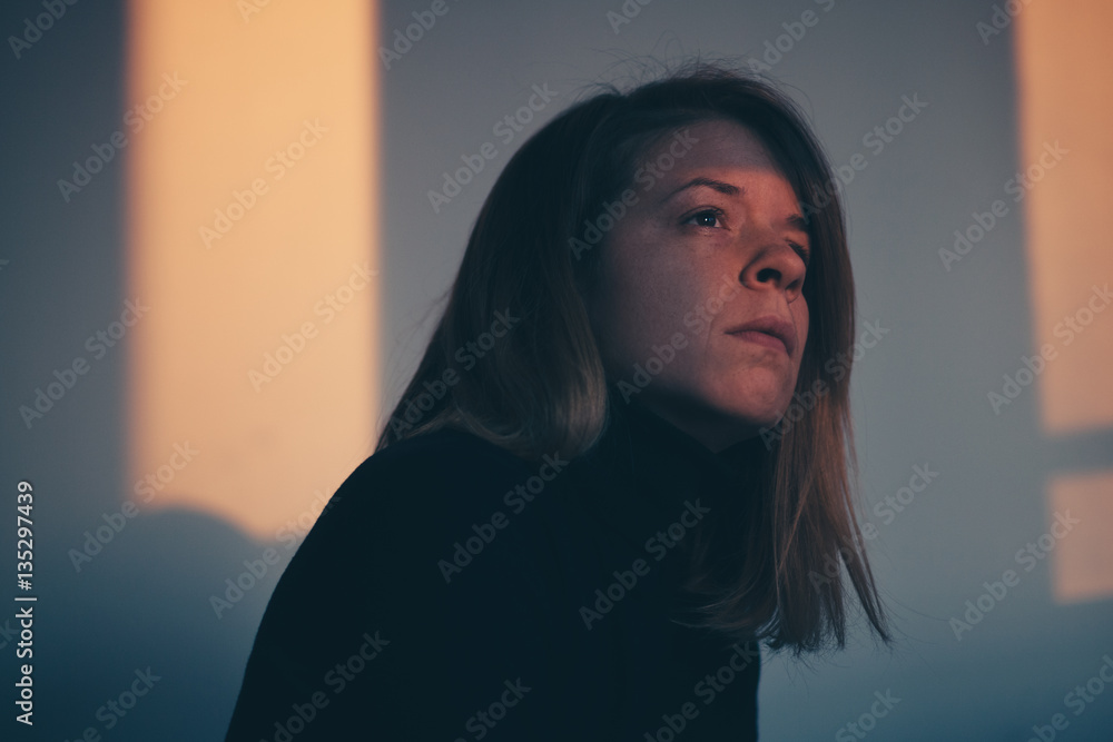 A woman sitting alone and depressed in window light A woman sitting alone and depressed in window light