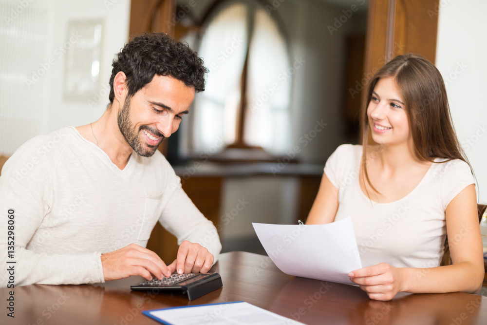 Happy couple calculating their expenses Happy couple calculating their expenses