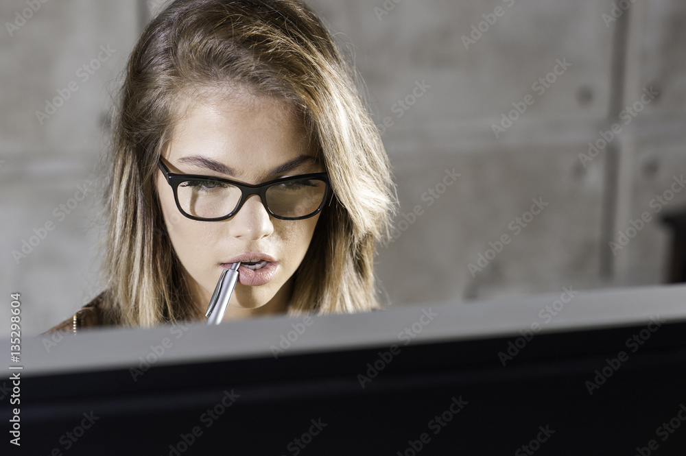 Beautiful young woman sitting at her desk working on a computer. Beautiful young woman sitting at her desk working on a computer.