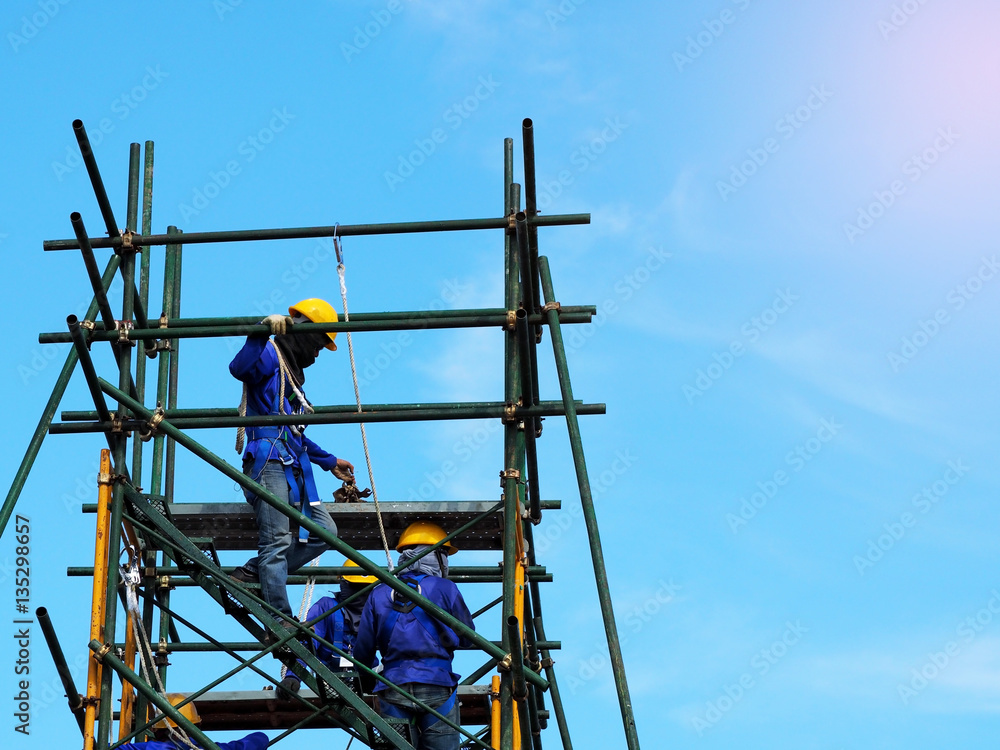 Construction workers working on scaffolding,Man Working on the Working at height with blue sky at construction site Construction workers working on scaffolding,Man Working on the Working at height with blue sky at construction site