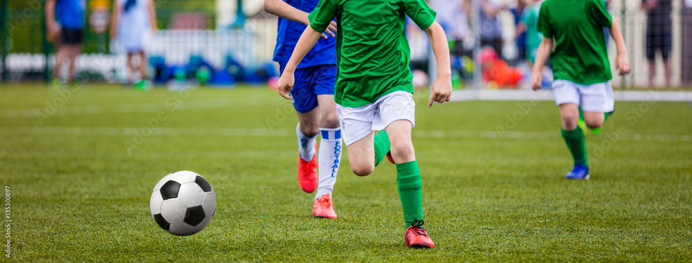 Young Boys Kicking Football on the Sports Field