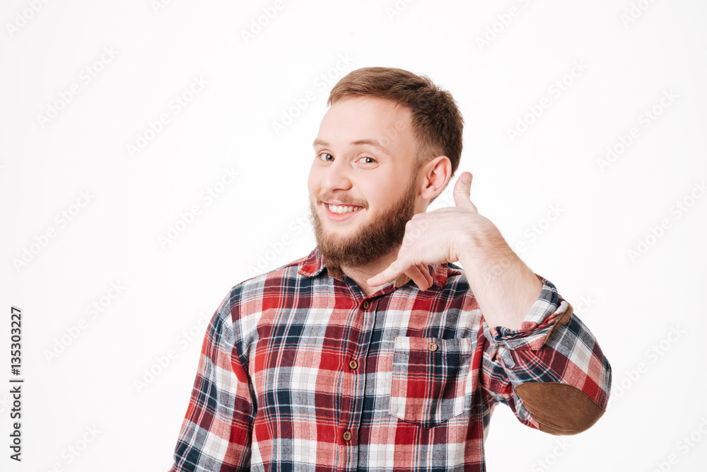 Smiling Bearded man in shirt showing phone sign Smiling Bearded man in shirt showing phone sign