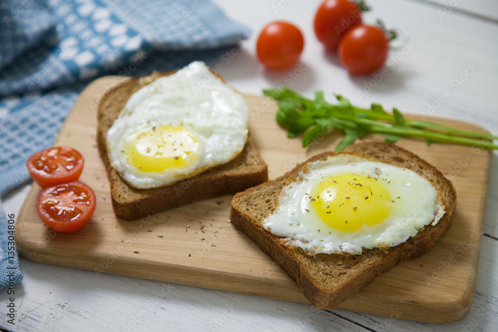 Healthy Breakfast: scrambled eggs on slices of whole-grain bread with arugula and tomatoes on a wooden Board