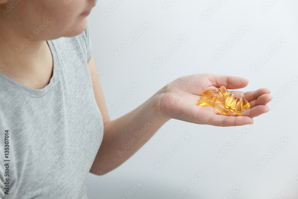 Obraz premium Hand is giving capsules Omega 3 on white background.