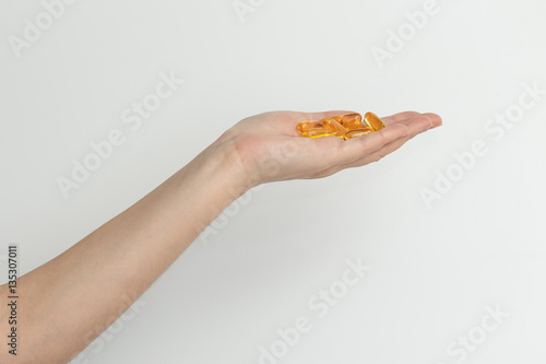 Hand is giving capsules Omega 3 on white background.