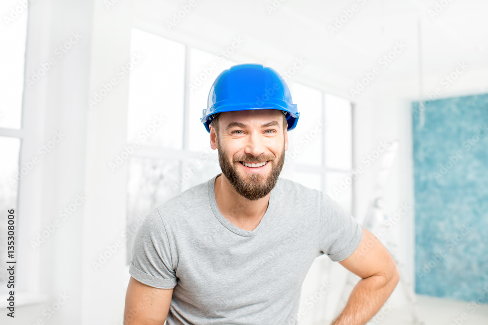 Portrait of a handsome builder, foreman or repairman in the helmet in the white interior Portrait of a handsome builder, foreman or repairman in the helmet in the white interior