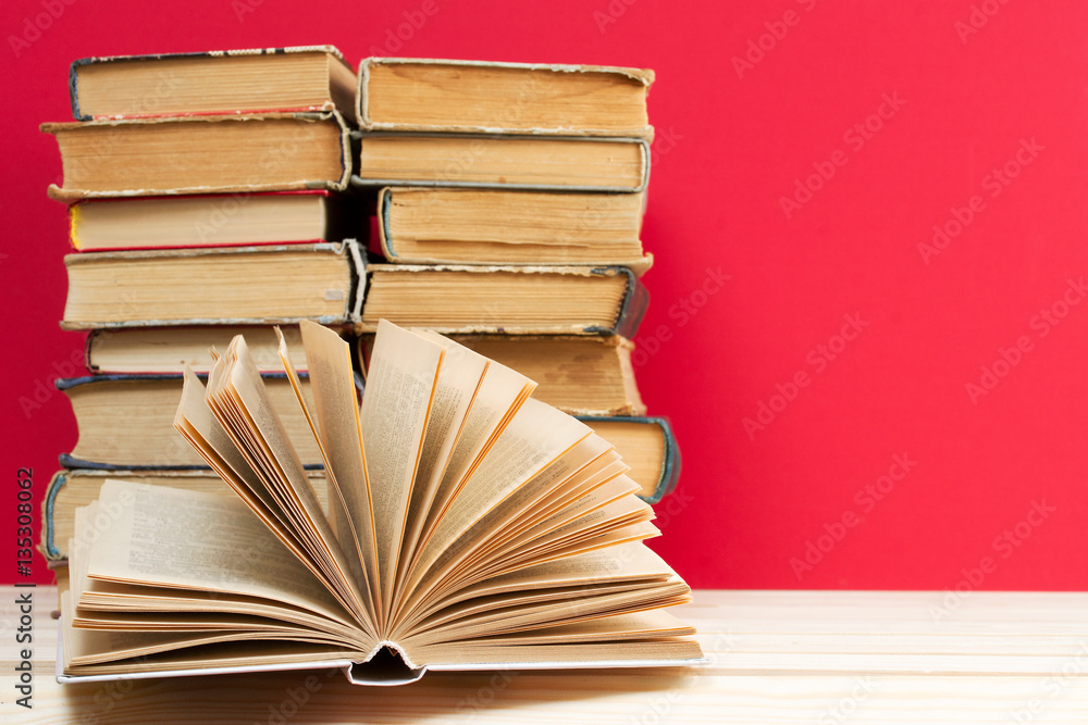 Obraz premium Open book, stack of hardback books on wooden table. Back to school. Copy space