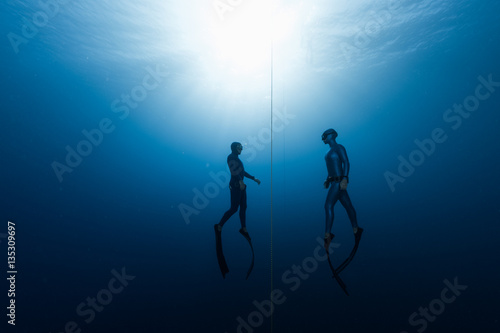 Two free divers, man and woman, ascending from the depth photo