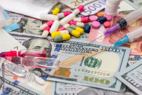 Фотография different pills on euro and dollar bills. medical concept.
