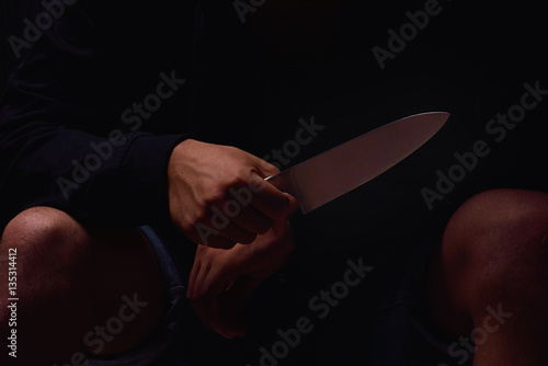 Closeup of a young man hand, holding a knife, about to attack, o