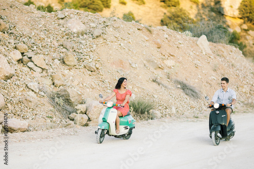 Happy young couple in love on retro motorbike driving togetger and ejoying the trip near the ocean. photo