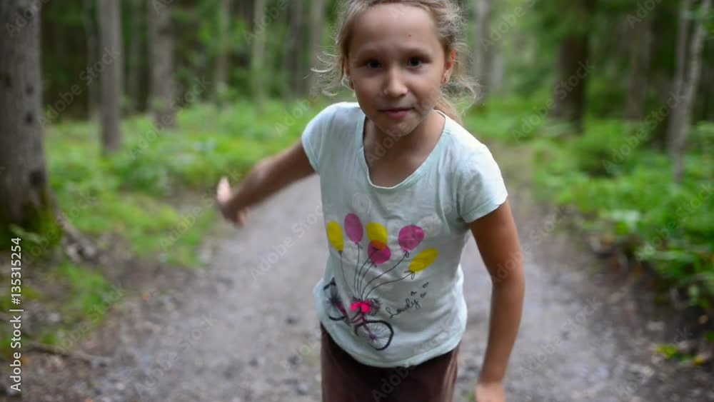Little girl child in summer forest running to the camera, stopping talking to you and showing welcoming gesture inviting to run together Little girl child in summer forest running to the camera, stopping talking to you and showing welcoming gesture inviting to run together