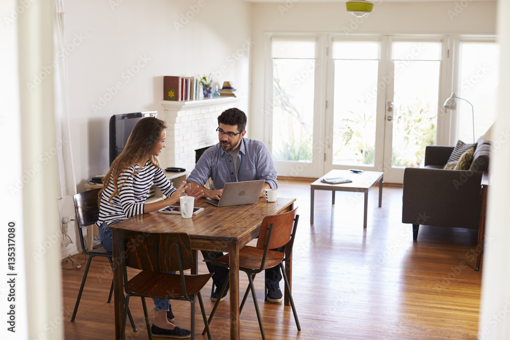 Couple Sitting At Table Using Laptop Together Couple Sitting At Table Using Laptop Together