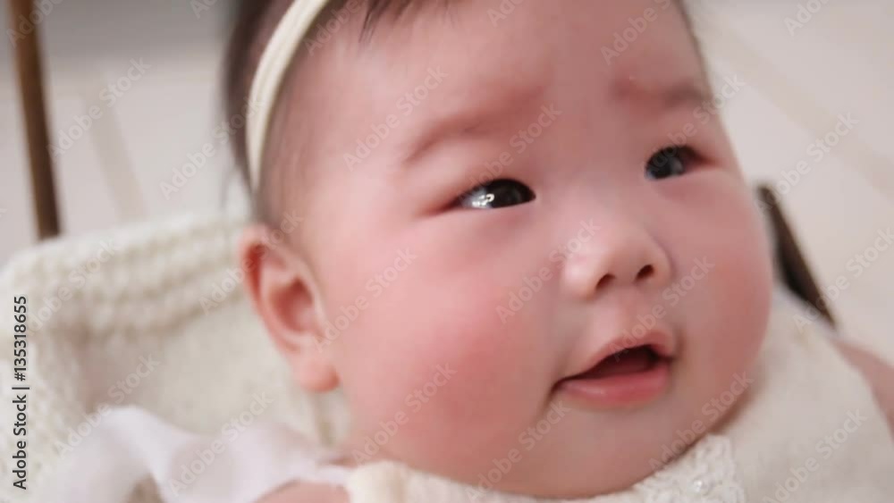 little asian baby girl lies in basket crib in dress and headband on a background of pink fur little asian baby girl lies in basket crib in dress and headband on a background of pink fur