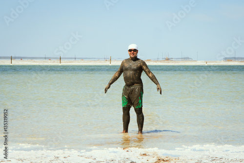 man takes a mud bath in the salty lake Baskunchak photo