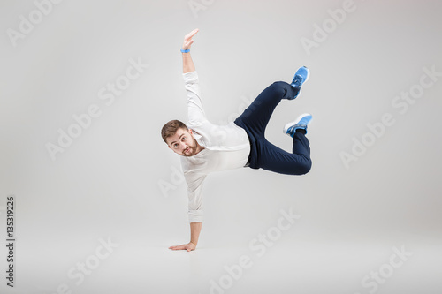 young happy businessman with beard in shirt break dancing on gre