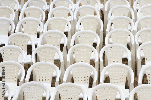 Many white plastic chairs put up for conference
