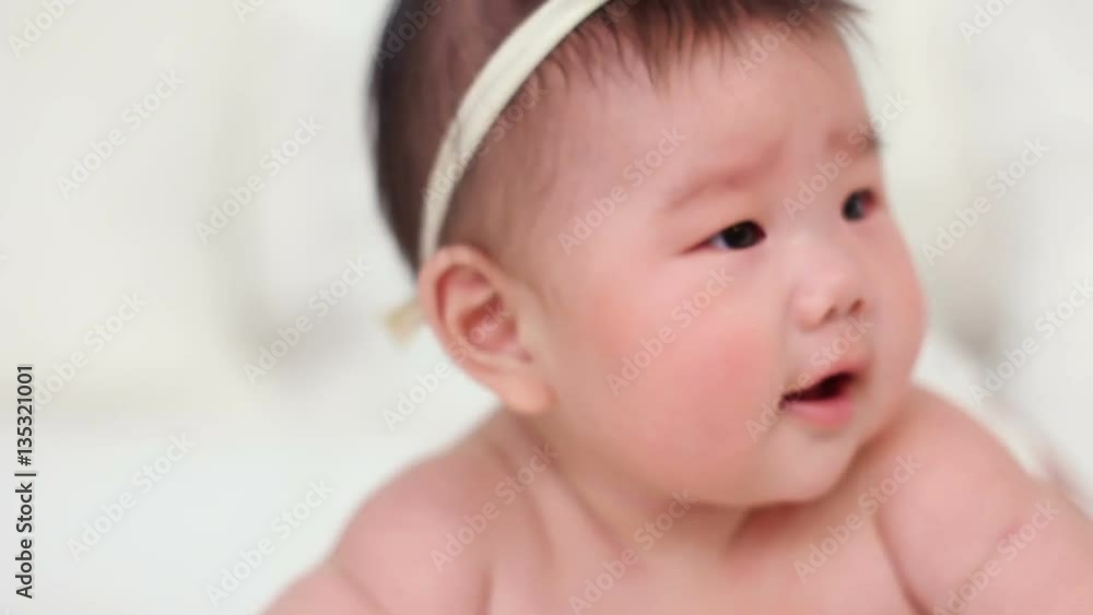 beautiful little baby girl asian smiling, asked, looking on a white bed beautiful little baby girl asian smiling, asked, looking on a white bed