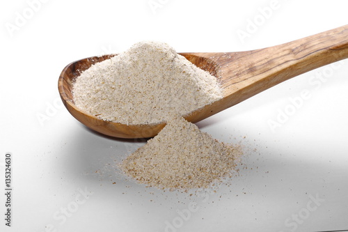 pile whole grain barley flour and wooden spoon isolated on white background