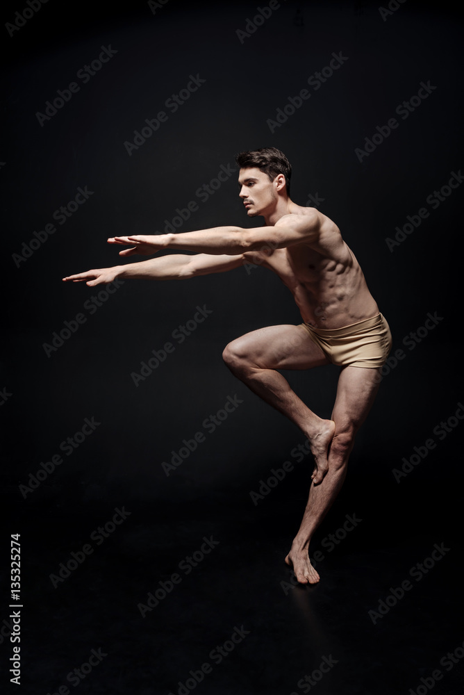Obraz premium Diligent concentrated dancer performing in the black studio