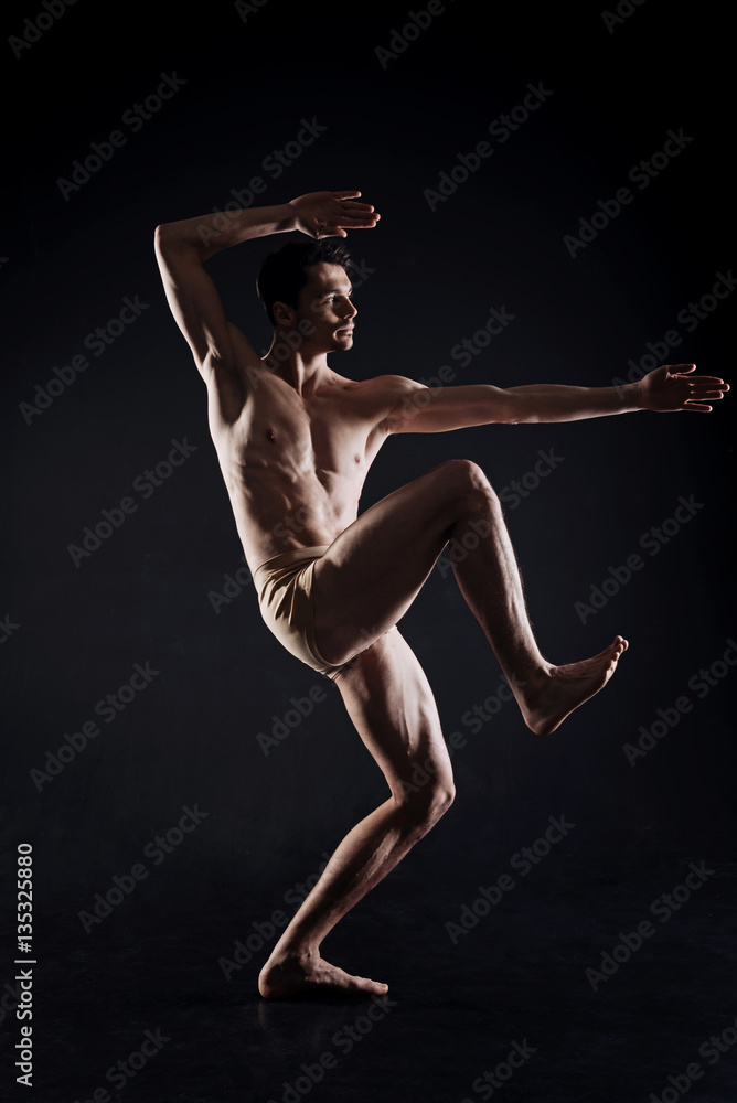 Powerful young athlete posing in the dark lighted studio