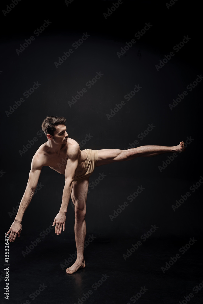 Young athlete dancing in the black colored studio