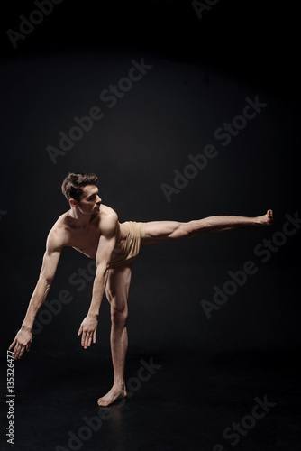 Young athlete dancing in the black colored studio