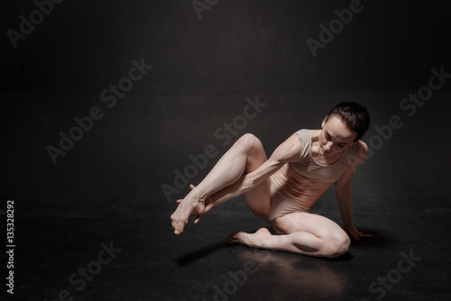 Unemotional young ballet dancer stretching in the studio