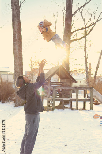 Father playing with child outside - throwing child in the air photo