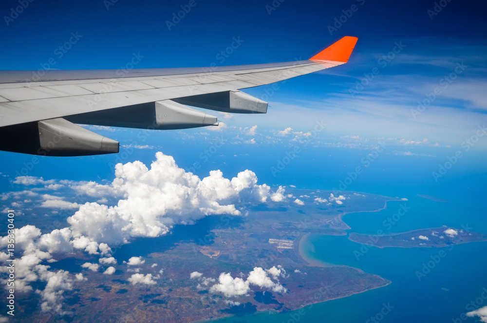 Fototapeta premium Airplane view of the wing of the plane Ocean island and clouds