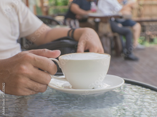 Male hands holding a cup of coffee on table