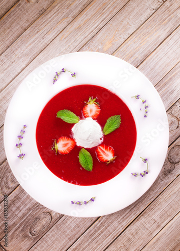 Strawberry soup with ice cream and mint. Pureed strawberries garnished with mint leaves topped with vanilla ice cream. Blended berries. Berry dessert. View from above, top studio shot