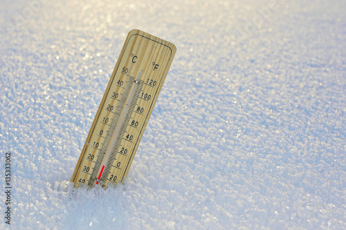 Mercury wooden thermometer stuck on snow shows very low temperatures. Temperatures in Celsius and Fahrenheit degrees. Cold winter weather. Twenty degrees under zero during the day.