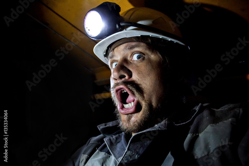 miner helmet shouts of fear/Portrait of angry coal miner shouting against a dark background in Russia