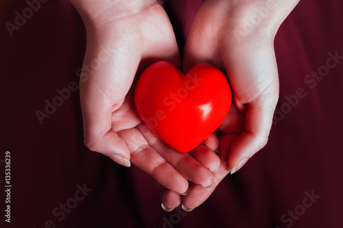 People  relationship and love concept - close up of womans cupped hands showing red heart